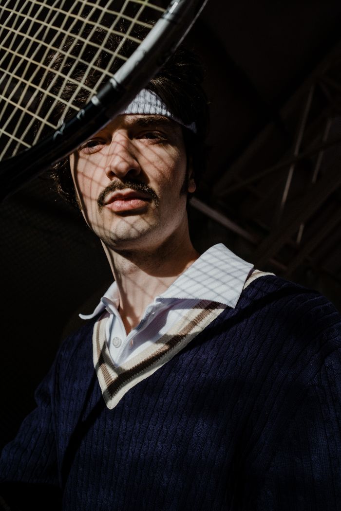 Portrait of a retro tennis player wearing a sweatband and holding a racket.